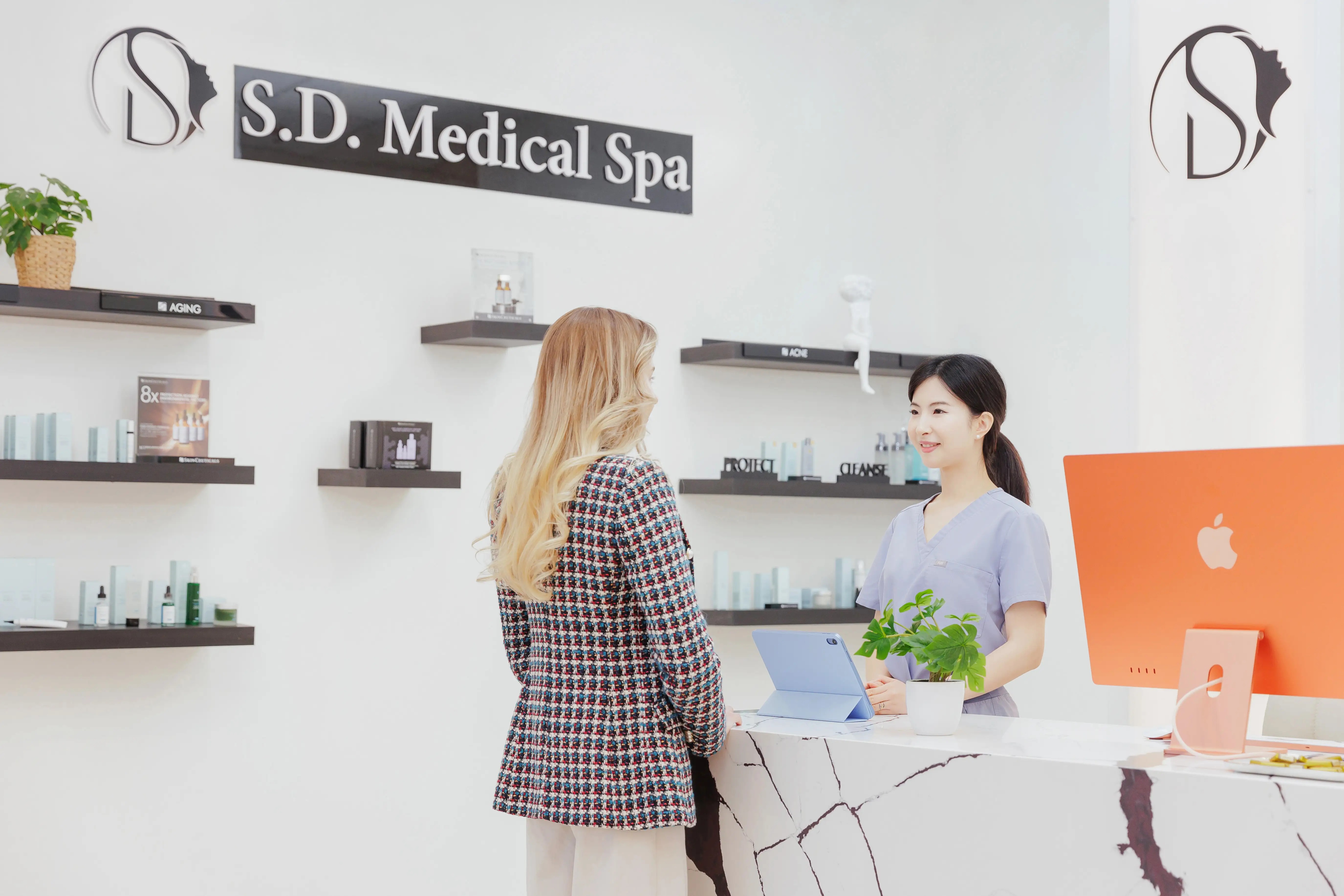 The reception area of S.D. Medical Spa in Oakville, with a nurse and a client at the desk.