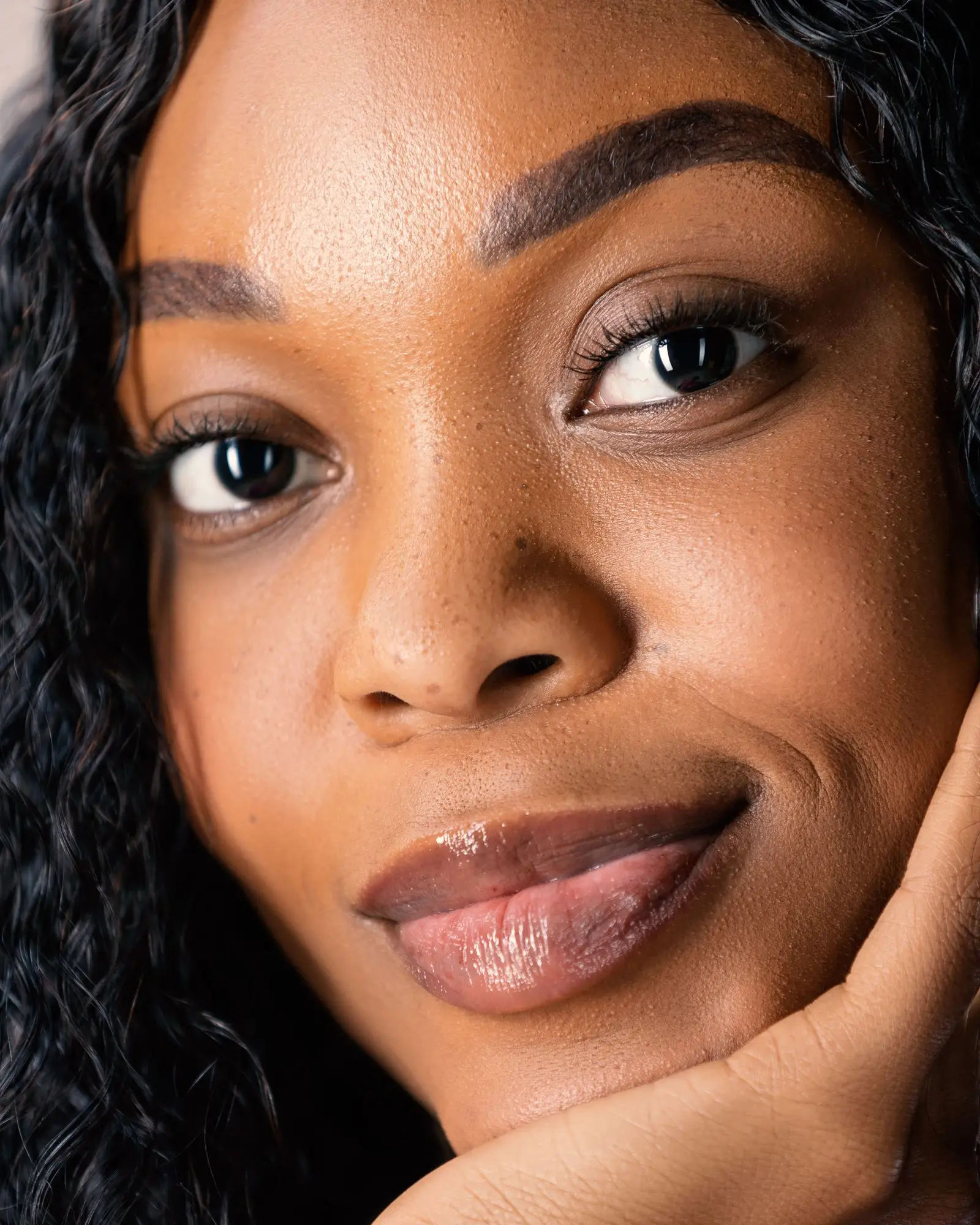 A smiling woman resting her cheek on her hand.