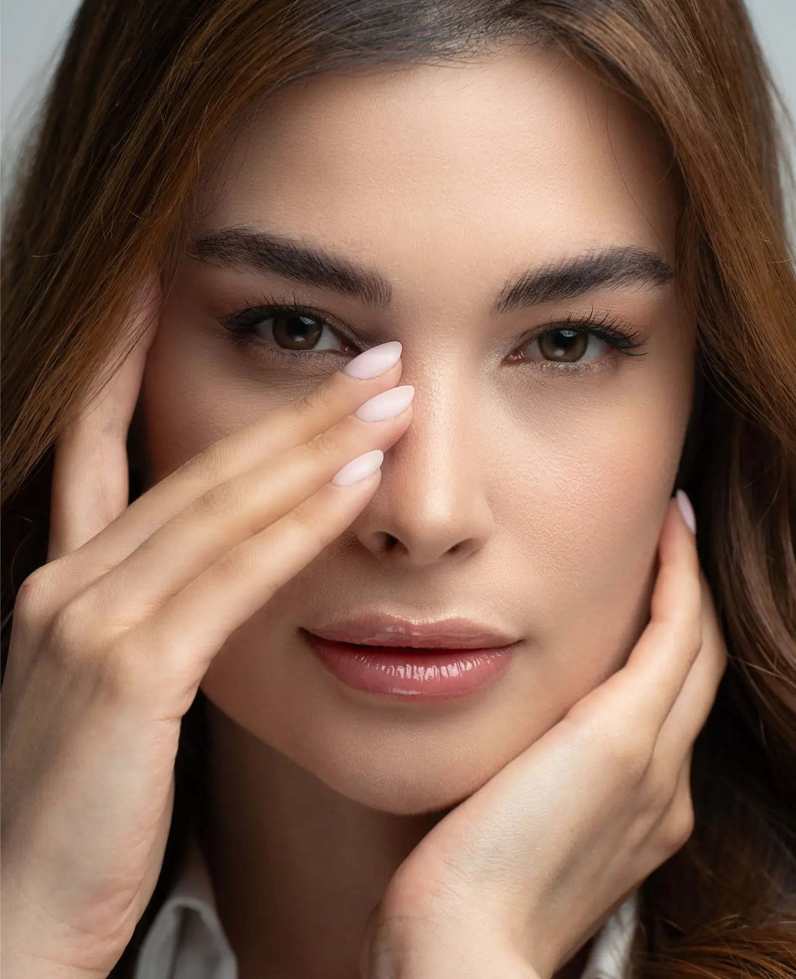 A woman with both hands resting lightly on her face.
